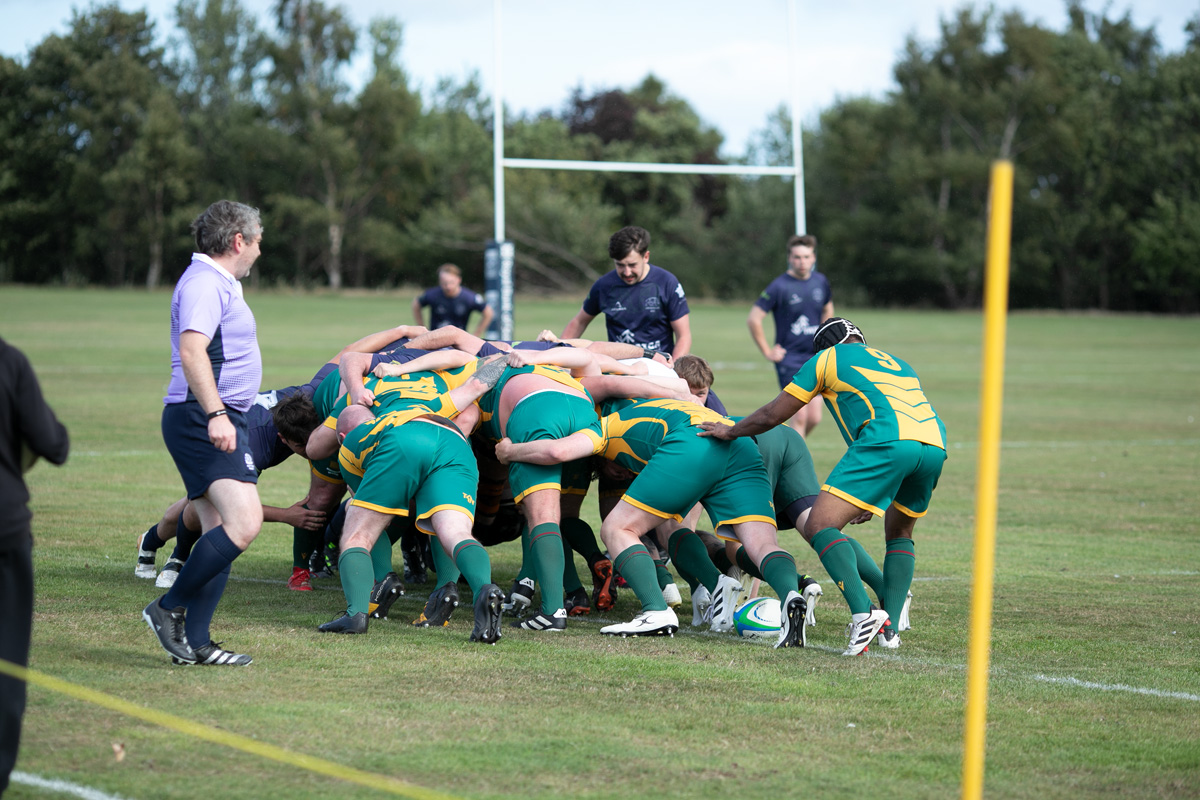 Rugby players contesting a scrum, with the referee alongside
